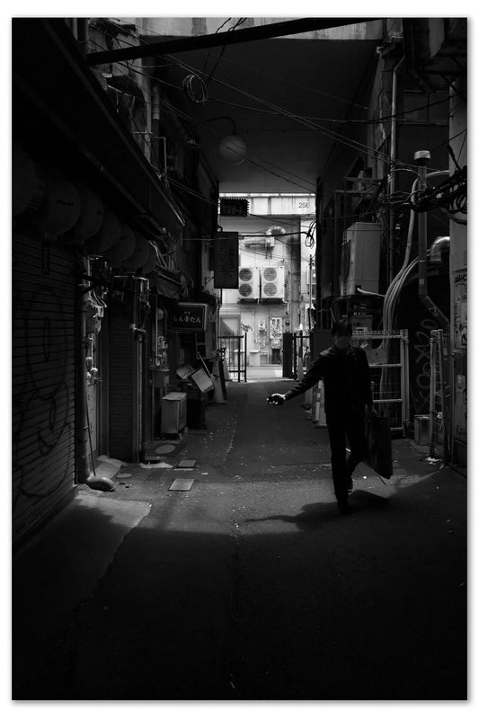 A person walking down a narrow alleyway in Ueno Market.