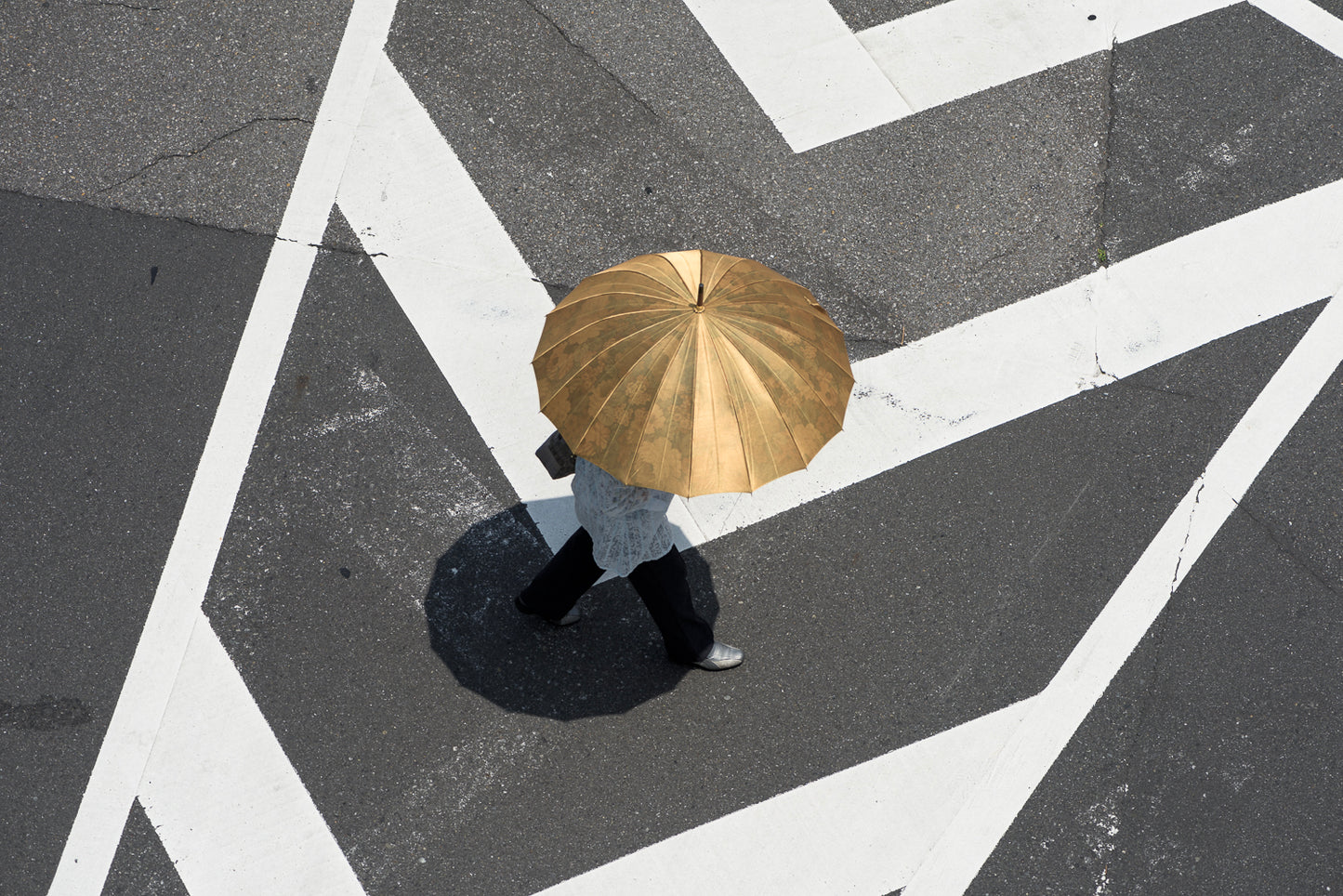 A woman walks in zebra stripes with a golden sun umbrella, Kawaguchi.