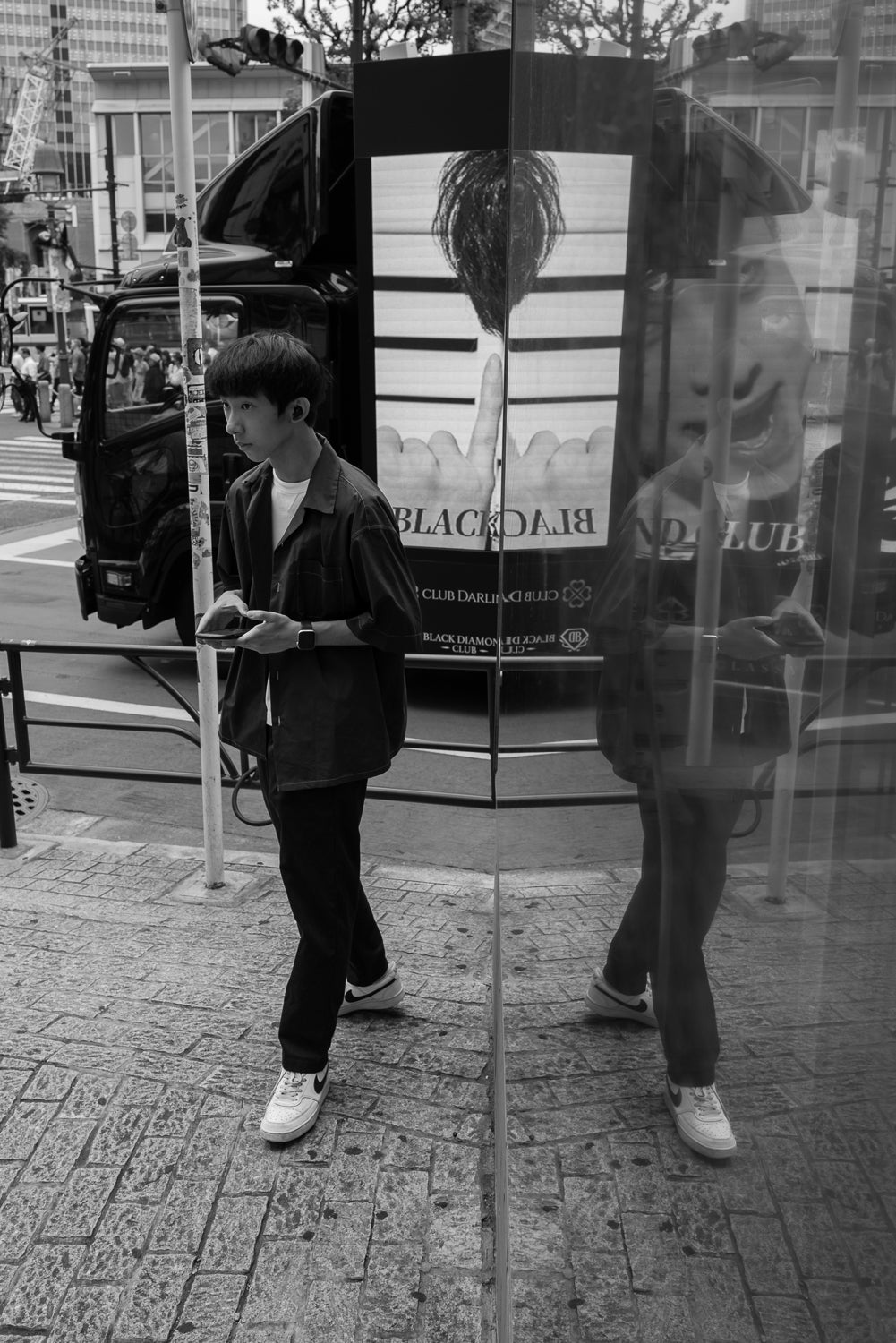Reflection of a young man and an advertisement truck in Shibuya.