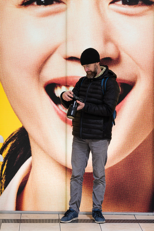 A photographer checks his camera in front of a billboard, Shiodome.