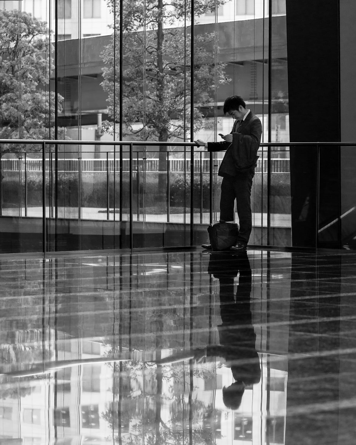Office worker and his reflection in a lobby, Shiodome.
