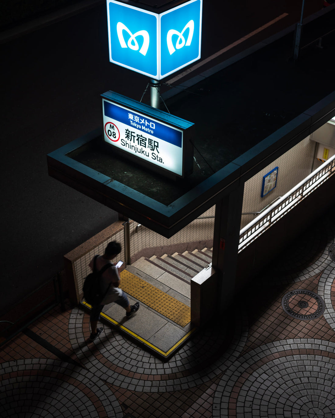 A man walks into a Shinjuku subway station at night