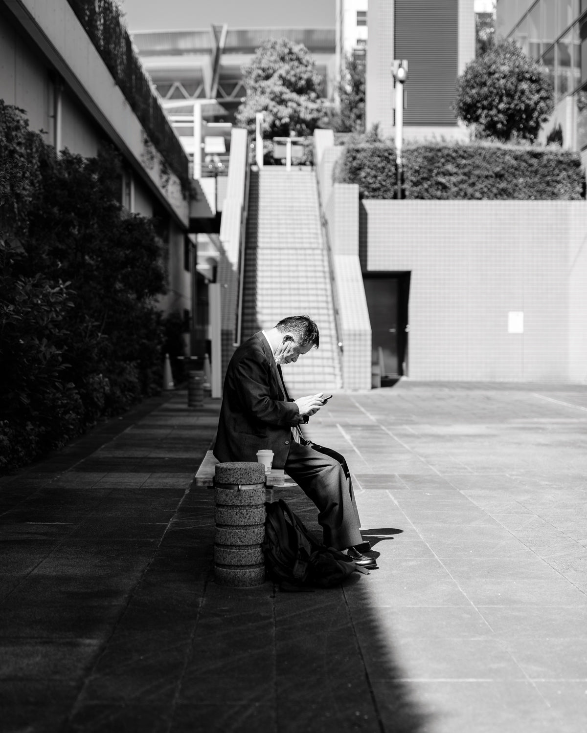 A man sits on his lunch break using a smartphone, half in light, half in shadow.