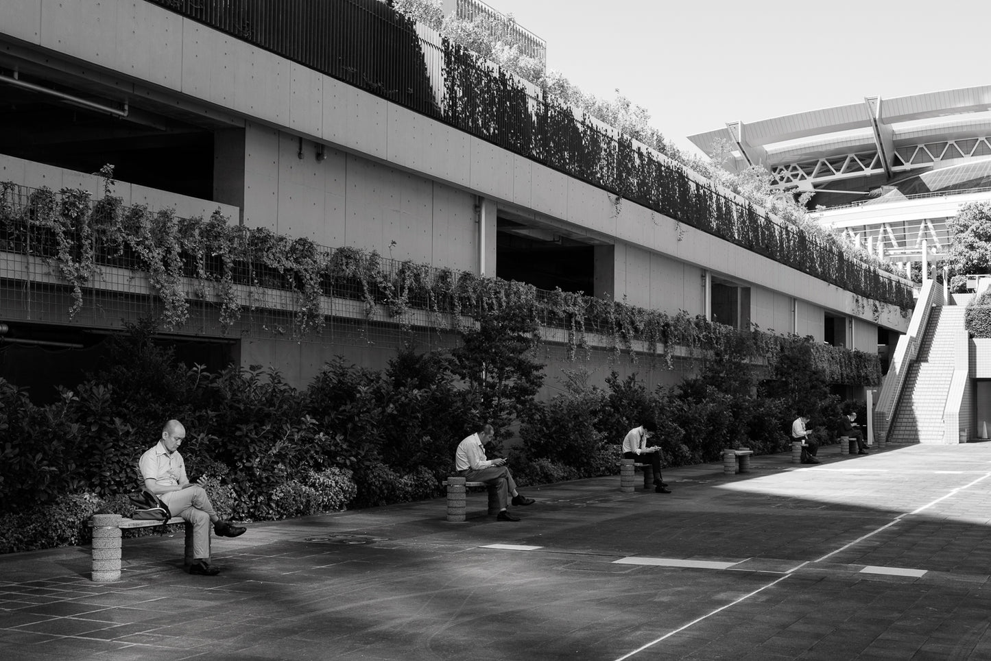 five men sit on their lunch breaks using smartphones. 