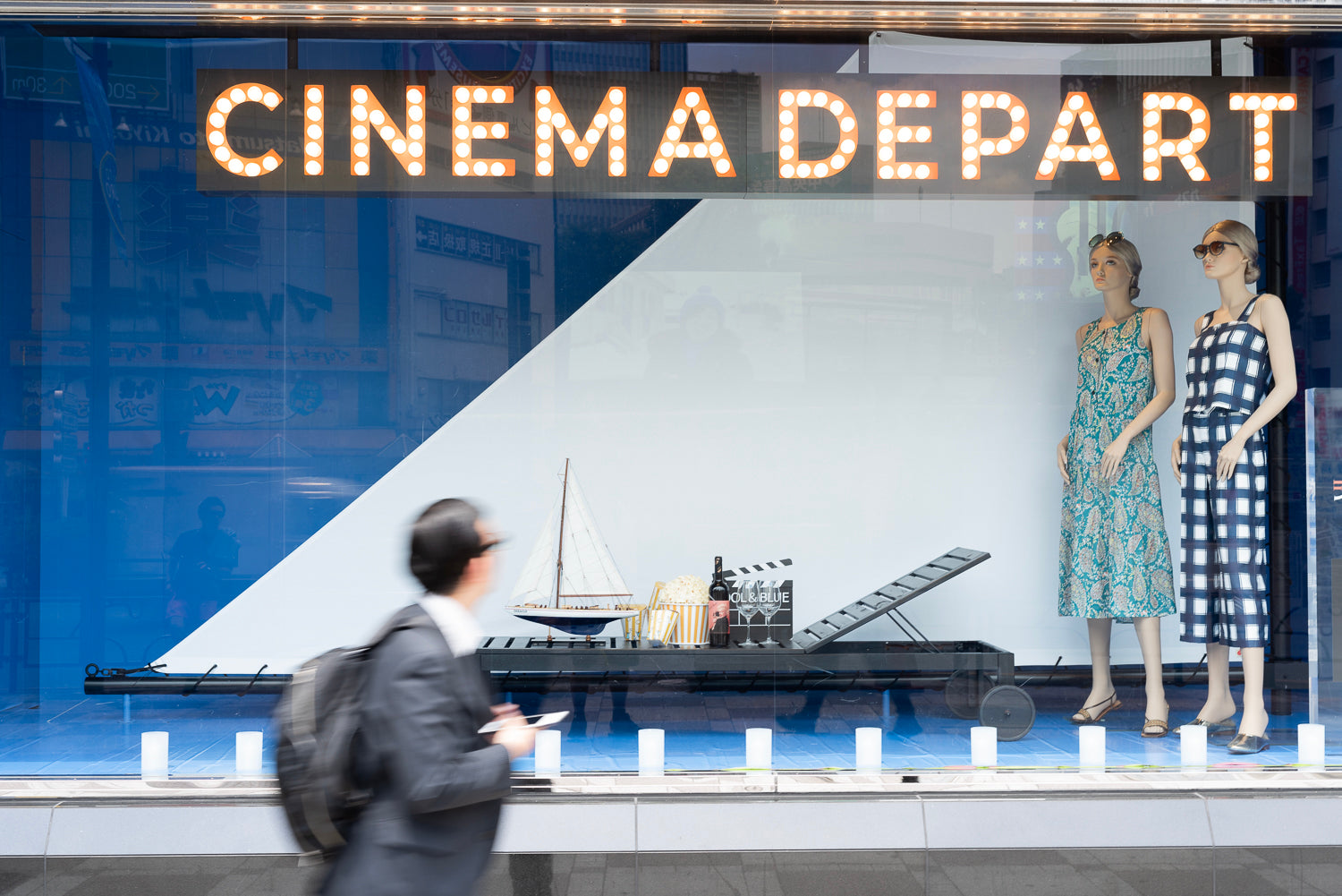 A man walks past the Ikebukuro Parco window display in a blur.