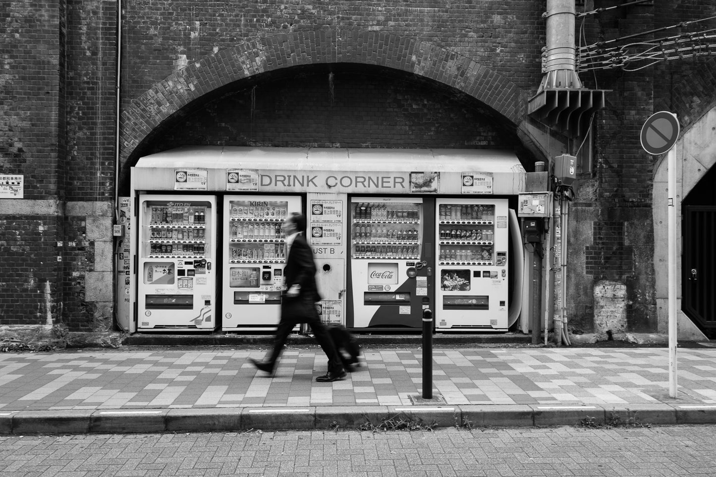 A man walking past vending machines in Kanda, Tokyo.